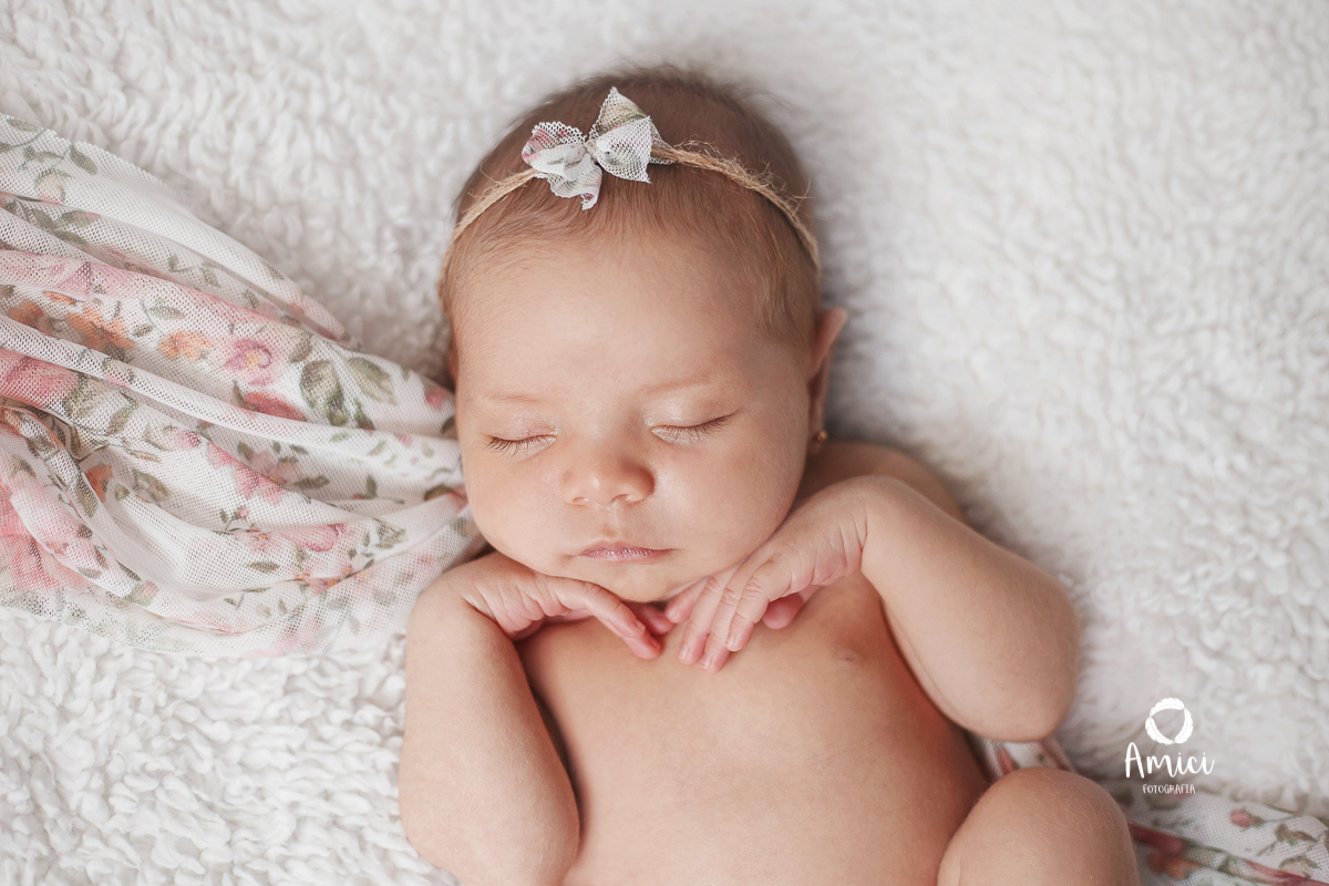 Fotografia newborn, pose barriguinha pra cima, com as mãos embaixo do queixinho.