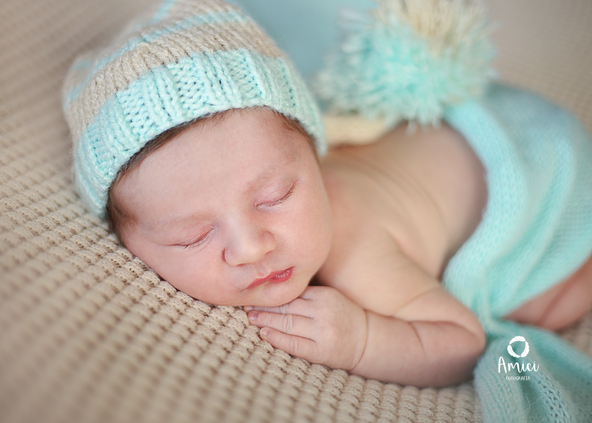 Bebê recém nascido, usando gorro verde água.