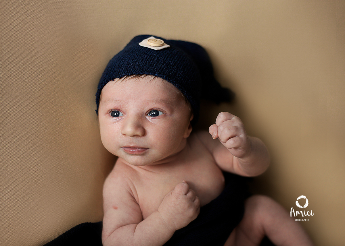Newborn, bebê recém nascido de olhos azuis, fotografado acordado, olhando para cima.