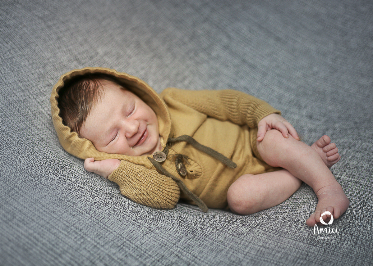 Fotografia newborn, recém nascido na pose de ladinho, com um lindo sorriso.