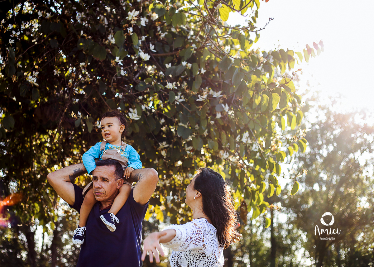 Fotografia preto da família, menino nos ombros do pai com luz entrando lateralmente.