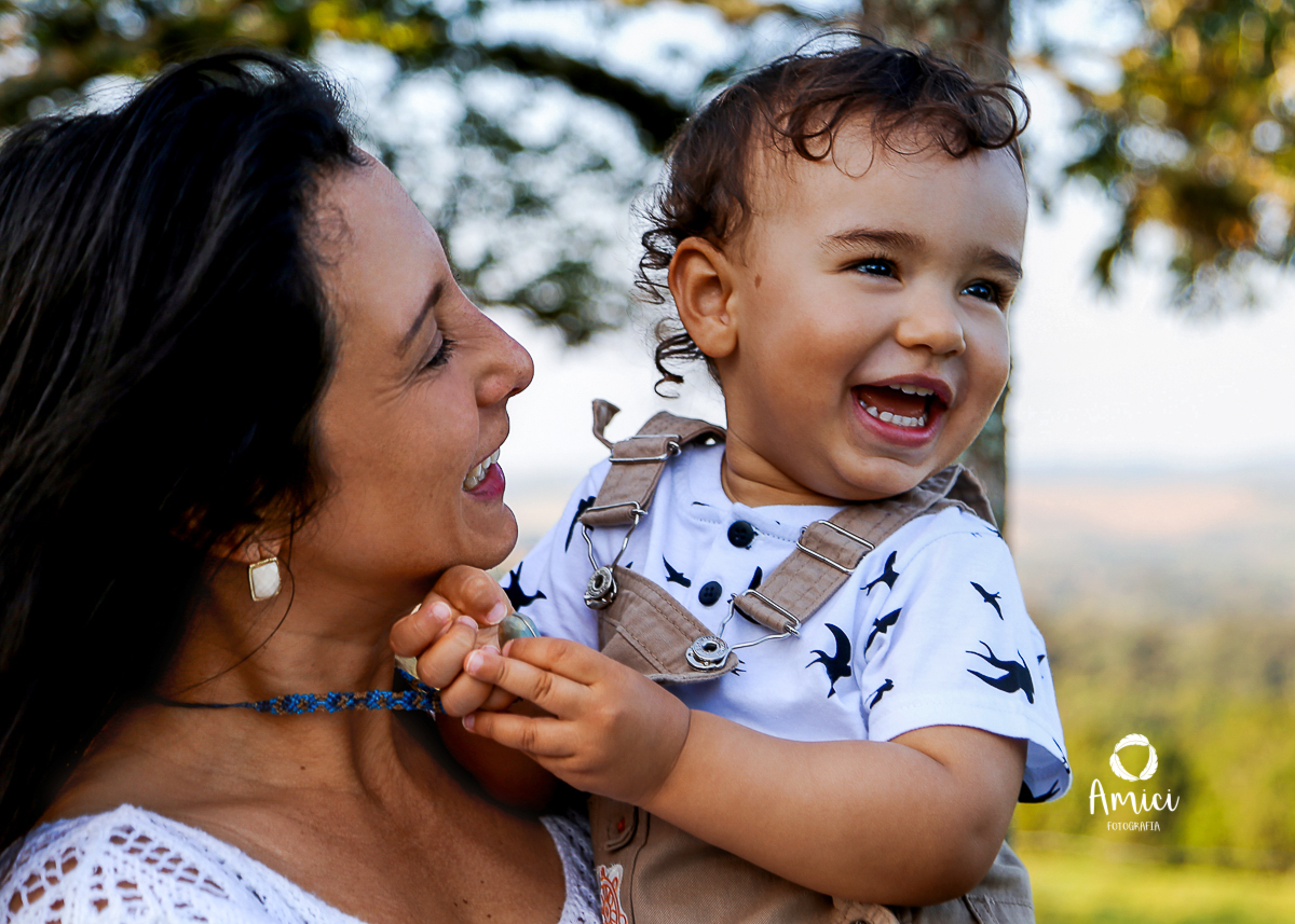 Fotografia de maternidade, destaque para o rosto de mãe e filho sorrindo.