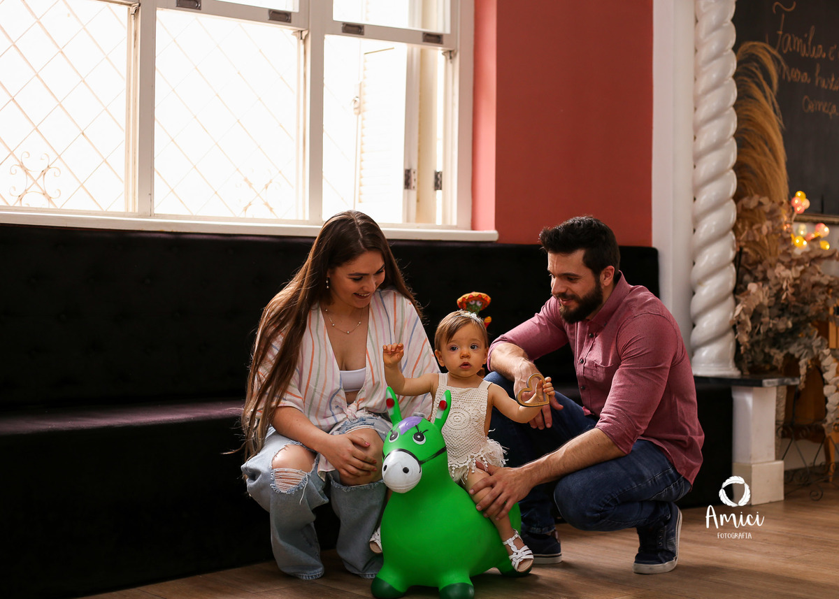 Fotografia de família, bebê brincando em cavalinho de brinquedo.