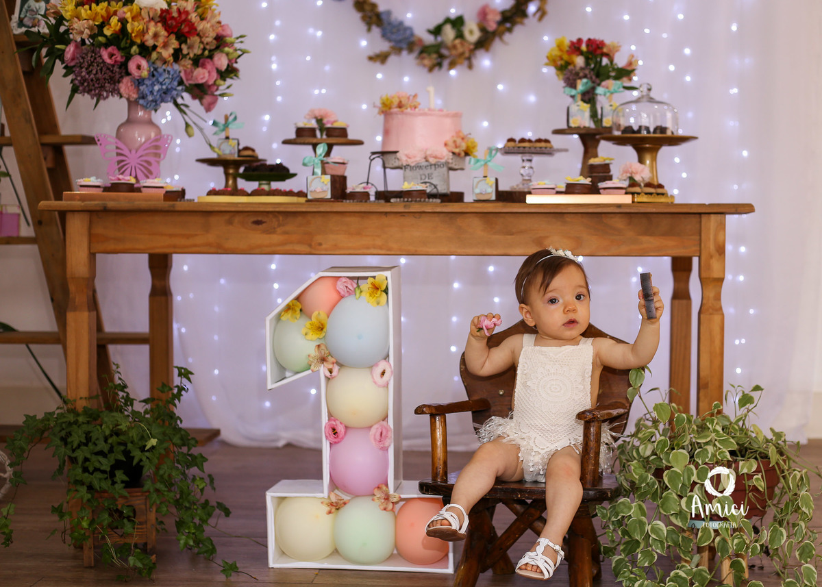 Festa infantil, bebê sentada em frente a mesa da decoração.
