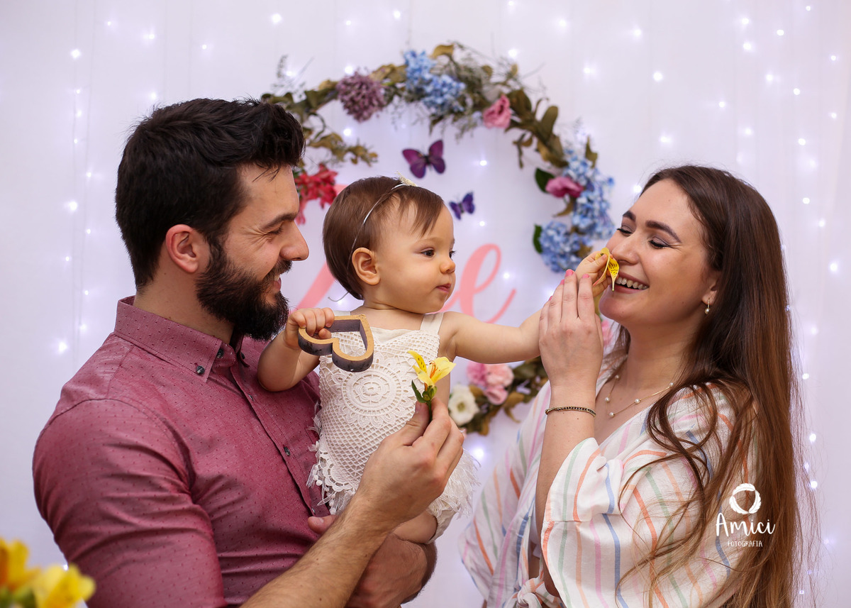 Fotografia de família, Bebê no colo do pai dando flor para a mãe.