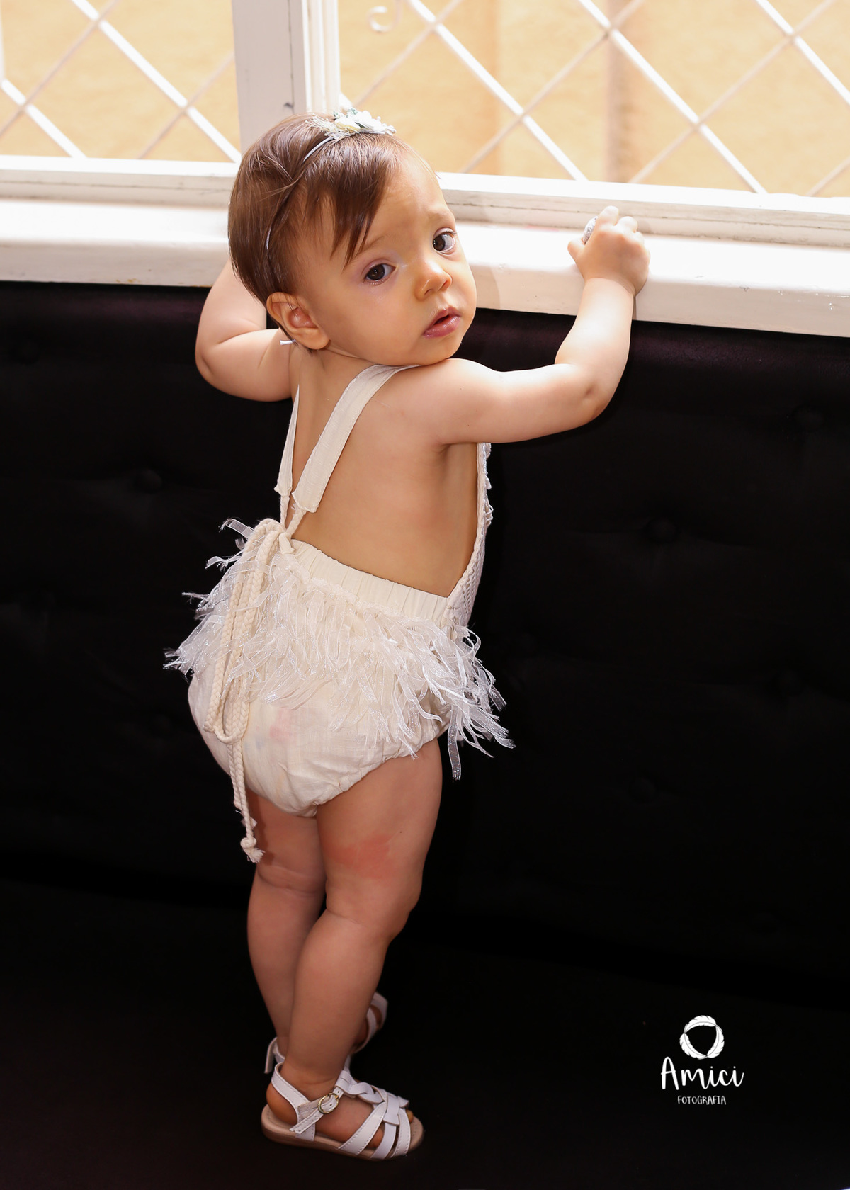 Fotografia infantil, bebê em pé na janela.