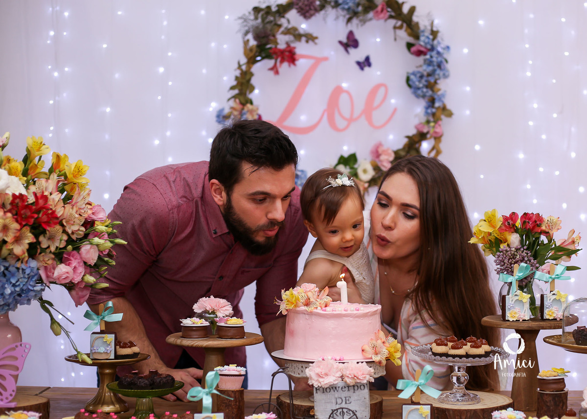 Festa infantil, pai, bebê e mãe assoprando a velinha.