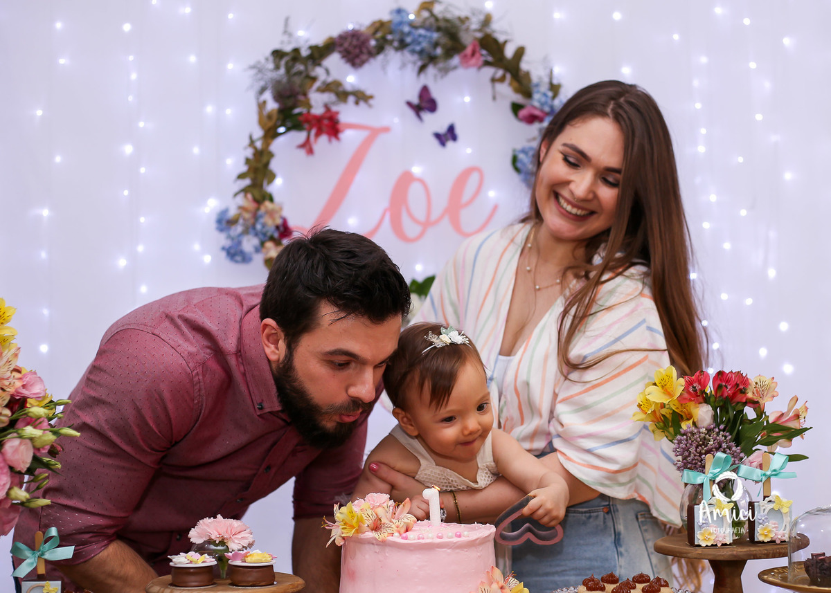 Festa infantil, pai assoprando , bebê olhando a fumaça e mãe assistindo.