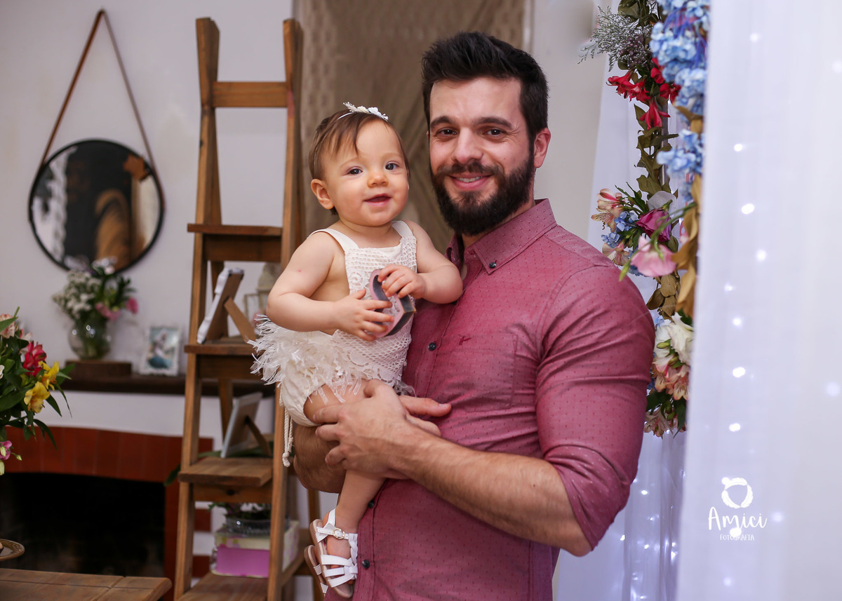 Festa infantil, bebê no colo do pai sorrindo.