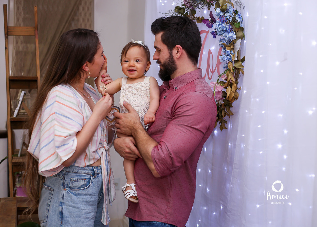 Festa infantil, mãe mordendo a mãozinha da bebê que ri.