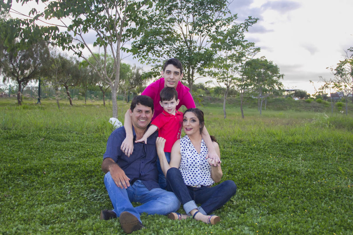 FAMILIA LINDA UNIDA NA FOTO SENTADOS NA GRAMA