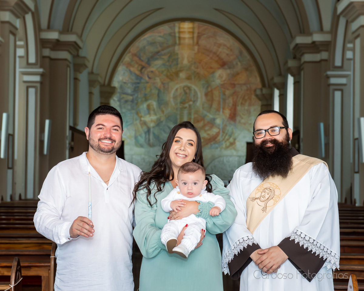 Foto da família com o bebê batizado e o Padre Franciscano dentro da igreja