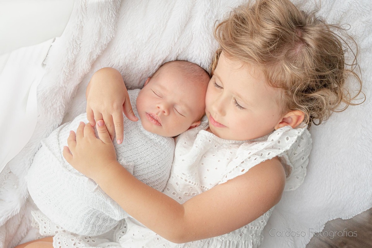 Menina Isis segura o bebê recém-nascido no colo durante ensaio fotográfico