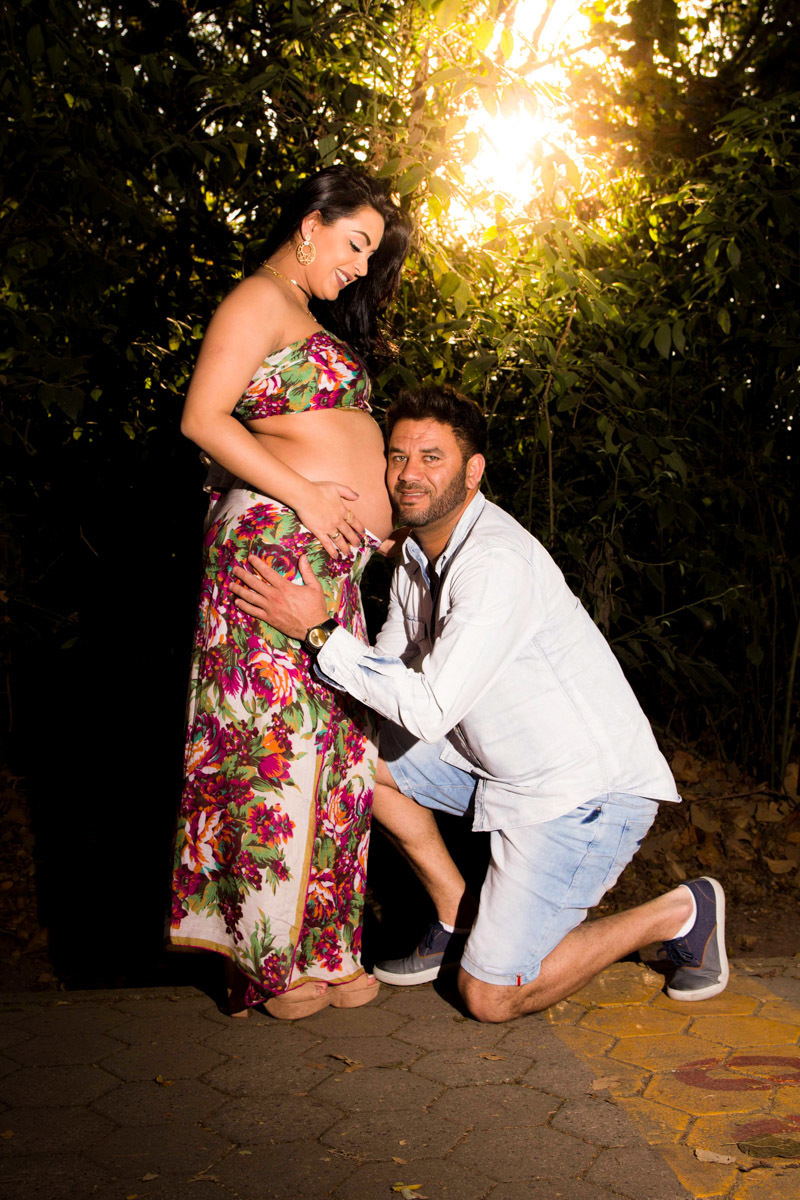 pai escutando o bebe na barriga da gestante no parque