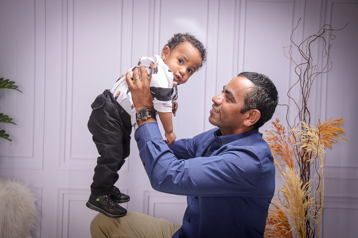 pai segurando filho no alto e olhando sorrindo