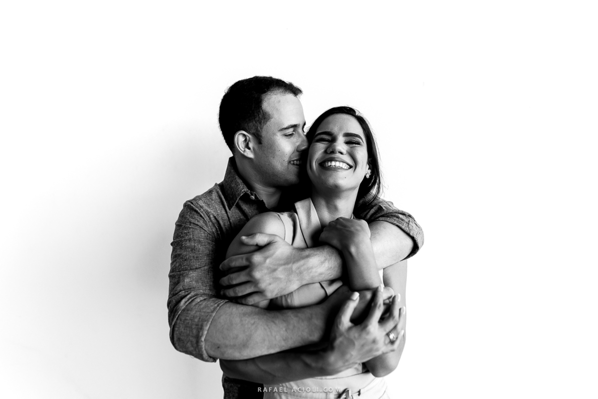 fotografia preto e branco com o noivo por trás da noiva abraçando ela e beijando a orelha dela