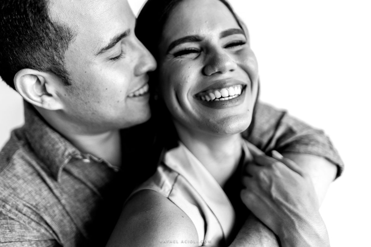 noivo abraçando a noiva e sorrindo com uma fotografia preto e branco