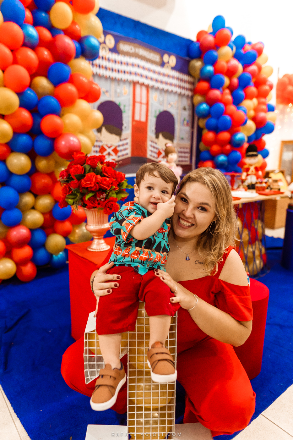Sorrindo meio tímido, Antônio coloca a mão no rosto enquanto a mãe o segura