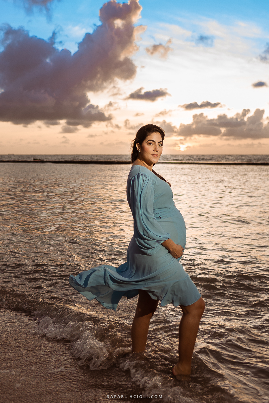 Roberta de perfil, segurando a barriga e olhando para câmera
