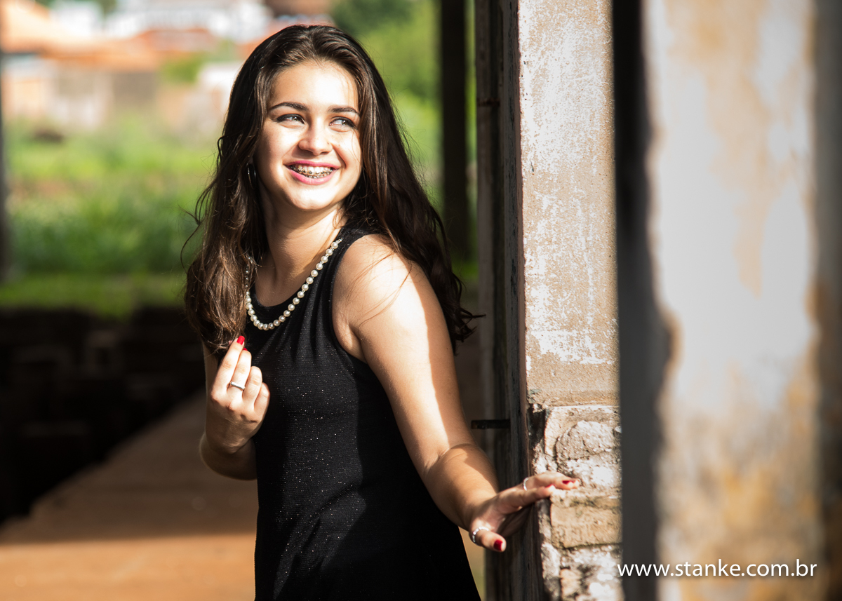Julia 15 anos, apoiada na parede olhando pela janela, e seu sorriso lindo, fotos feitas por Pedro Stanke, dentro da  Rotunda, em Campo Grande-MS.