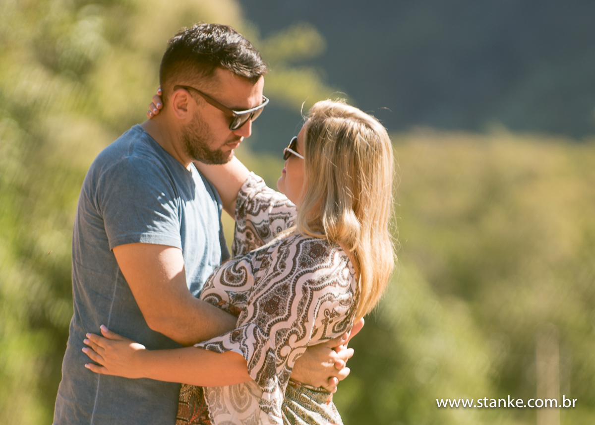 Os noivos abraçados e se olhando, e a noiva coma mão na cabeça do noivo e ao fundo a serra desfocada.. Em Piraputanga-MS