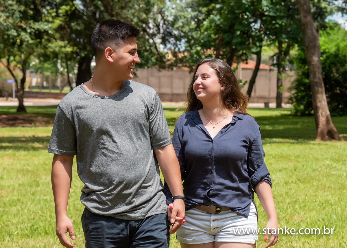 Noivos caminhando a vontade e sorrindo um para o outro.  Ensaio Pré-wedding ou pré-casamento de Mariana e Davi, ensaio realizado no Bosque da Paz, Carandá Bosque, Campo Grande-MS, fotos feitas por Pedro Stanke.