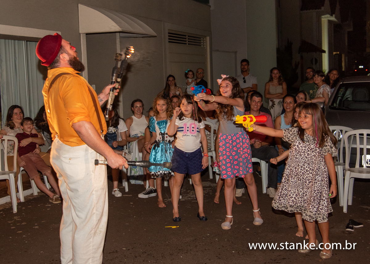 O palhaço Pepa e a crianças apagando as tochas de malabarismo com pistola d'agua, na festa Helena e Bianca, no jardim da avó, em Campo Grande-MS, fotos feitas por Pedro Stanke.