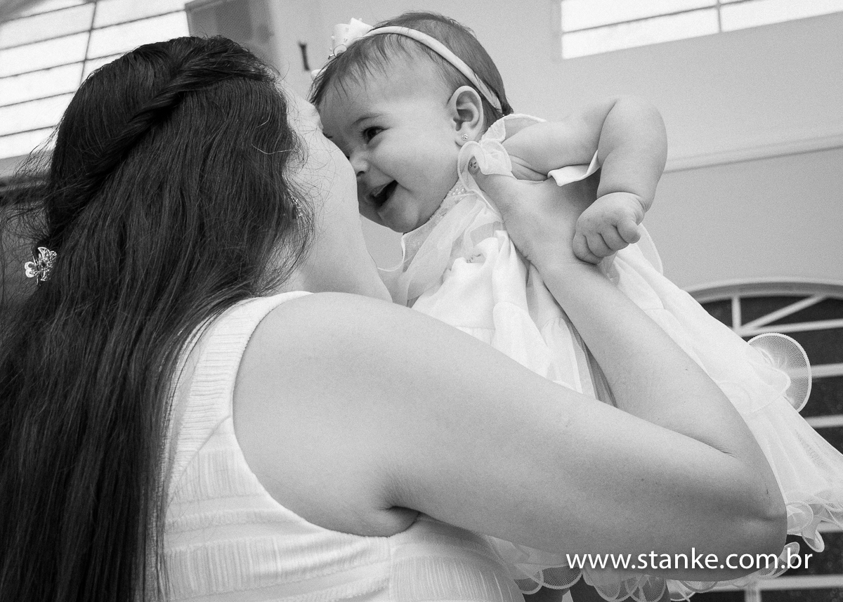 Gabriella sendo levantada pelo braços pela sua mãe, com os rostos bem pertinhos, em preto e branco, na Igreja Santíssima Trindade, em Campo Grande-MS. Fotos feitas por Pedro Stanke.