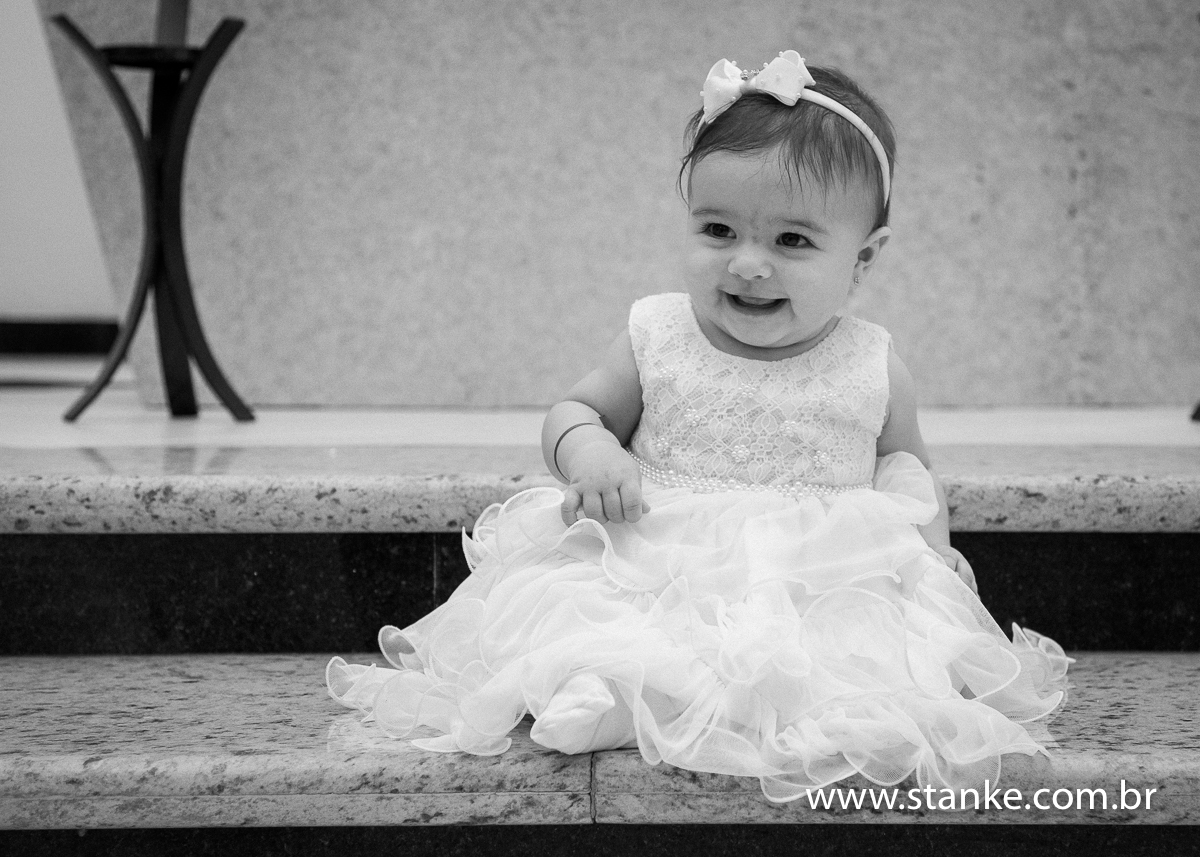 Uma foto preto e branco da Gabriella sentada no chão, em frente ao altar, com lindo sorriso, na Igreja Santíssima Trindade, em Campo Grande-MS. Fotos feitas por Pedro Stanke.