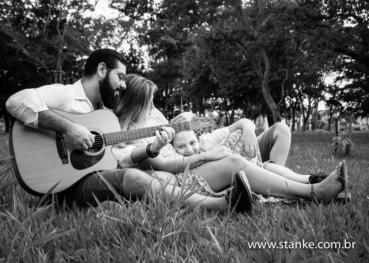 Família Fedrizzi, ensaio externo, Silvio no violão, Enzo no colo da Jennifer. Fotos feitas no Carandá Bosque, Campo Grande, MS, por Pedro Stanke. 