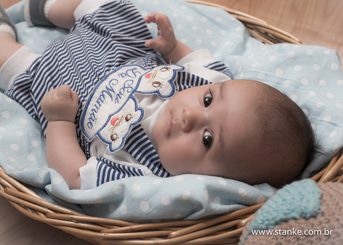 Newborn do Isaque com 28 dias. Isaque com roupinha deitadinho dentro da cesta e olhando para câmera. Fotos feitas em Campo Grande-MS, pelo Fotógrafo Pedro Stanke.