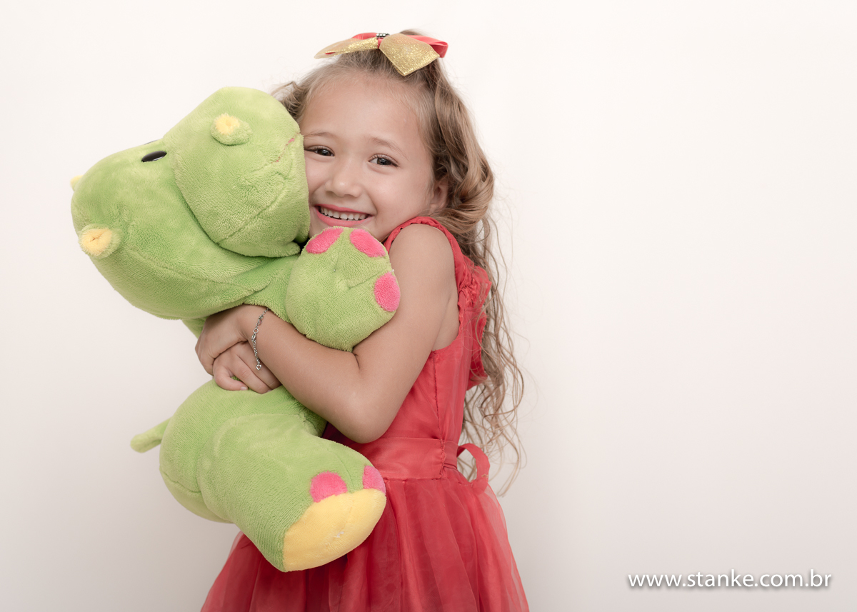 Ensaio Manu 9 anos, Manu dando um gostoso abraço no boneco de hipopótamo verde. Fotos feitas em Campo Grande-MS, pelo Fotógrafo Pedro Stanke.