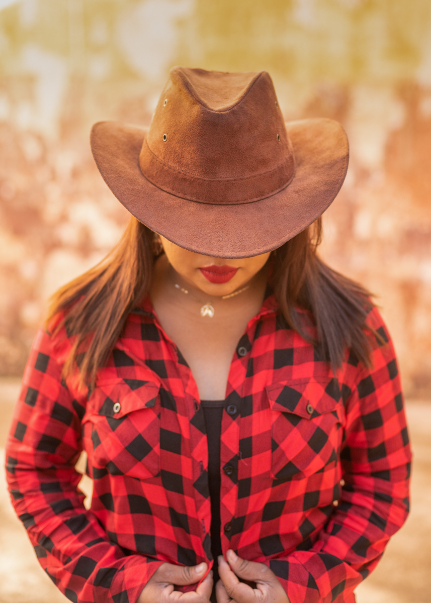 Ensaio externo Danielly, Danny de frente com a aba do chapéu escondendo os seu olhos de cabeça baixa e sua camisa xadrez vermelha com preto. Valorizando seus enormes lábios. Fotos realizadas em Campo Grande-MS, feitas por Pedro Stanke.