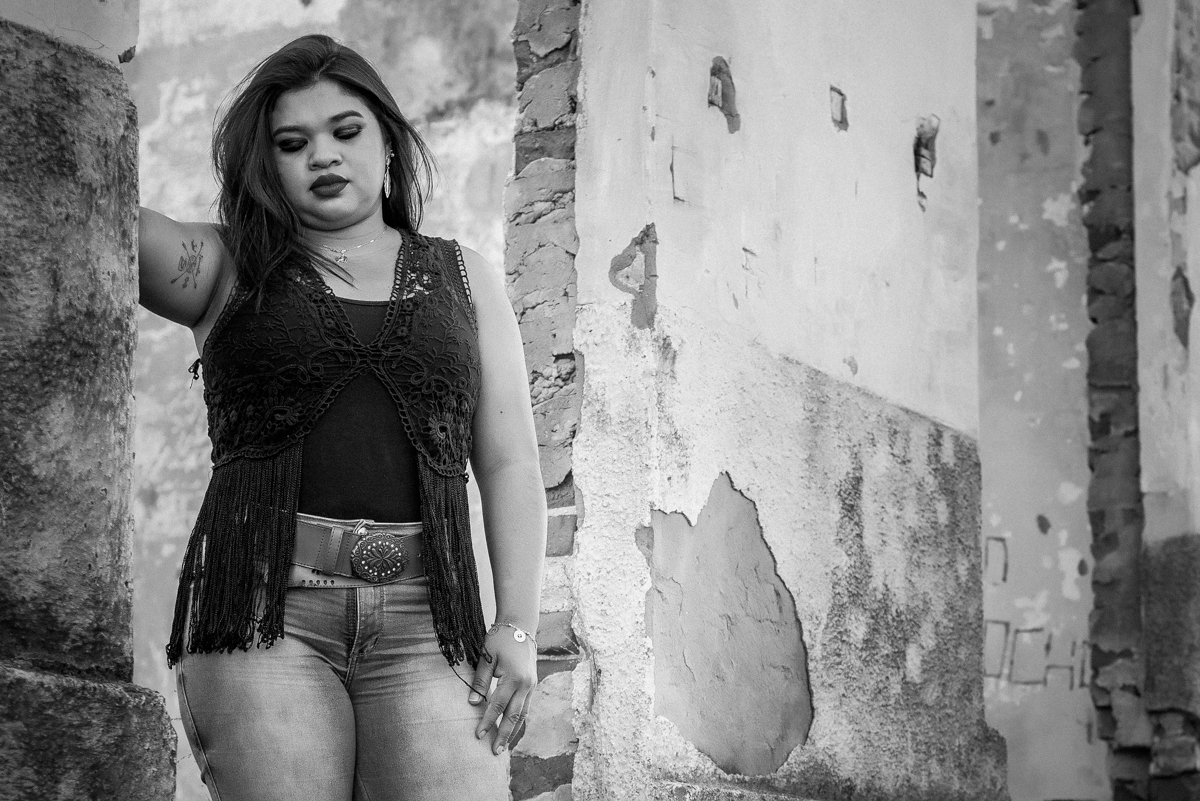 Preto e Branco Danny de pé na entrada da estação em com roupa country, uma regata e blusa também preta, calca Jeans, e botas, cum dos braços apoiado na parede. Fotos realizadas em Campo Grande-MS, feitas por Pedro Stanke.