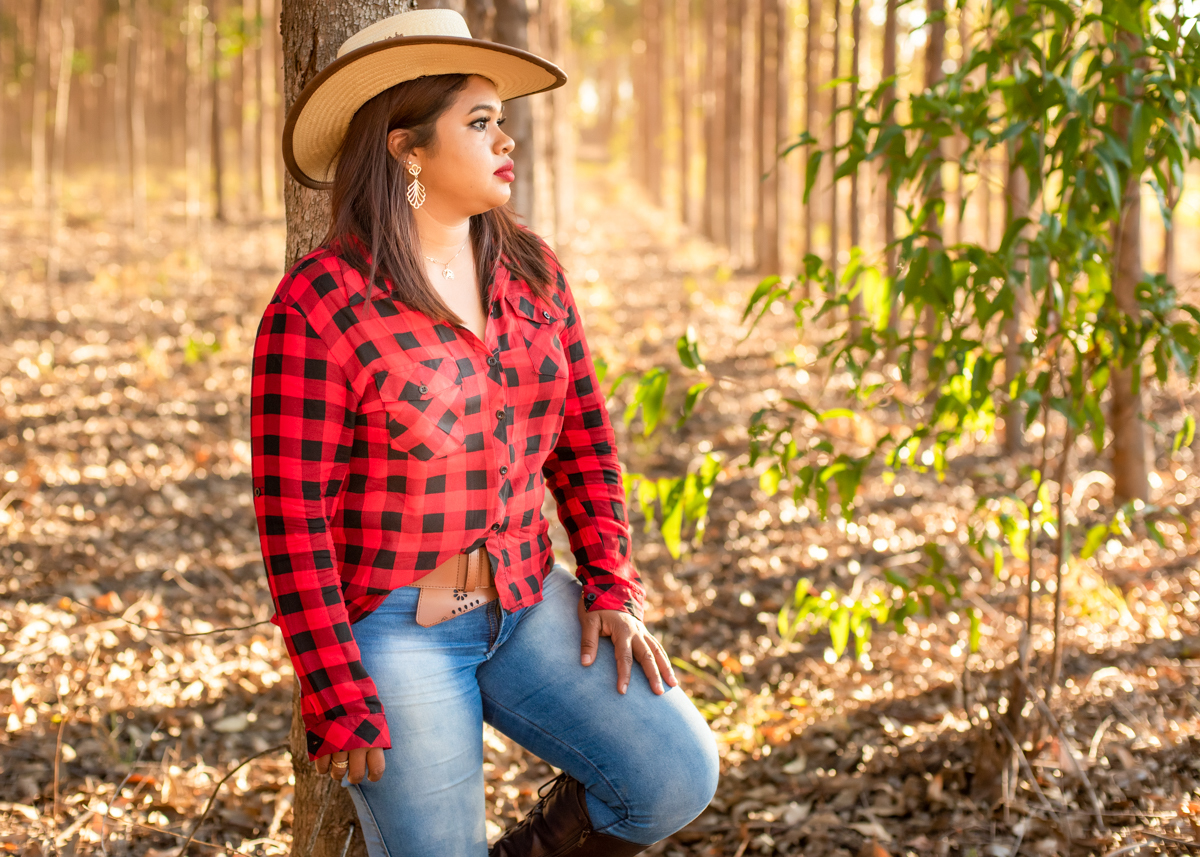 Ensaio externo da Danny entre os eucaliptos com sua camisa xadrez vermelha e preta e seu chapéu, calça Jeans e botas. com olhar distante. Fotos realizadas em Campo Grande-MS, feitas por Pedro Stanke.