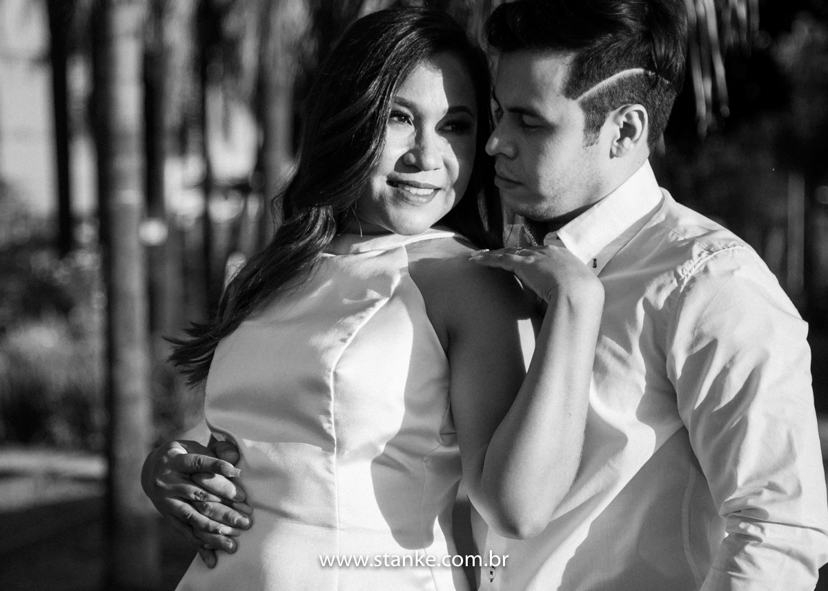 Ensaio pós casamento de Giseli e Aurélio, Foto Preto e Branco. A Giseli encostada de costas no Aurélio e ele com umas das mãos no bolso, e outra abraçando ela e se olhando. Fotos feitas no Memorial Ferroviário, em Campo Grande-MS, por Pedro Stanke.