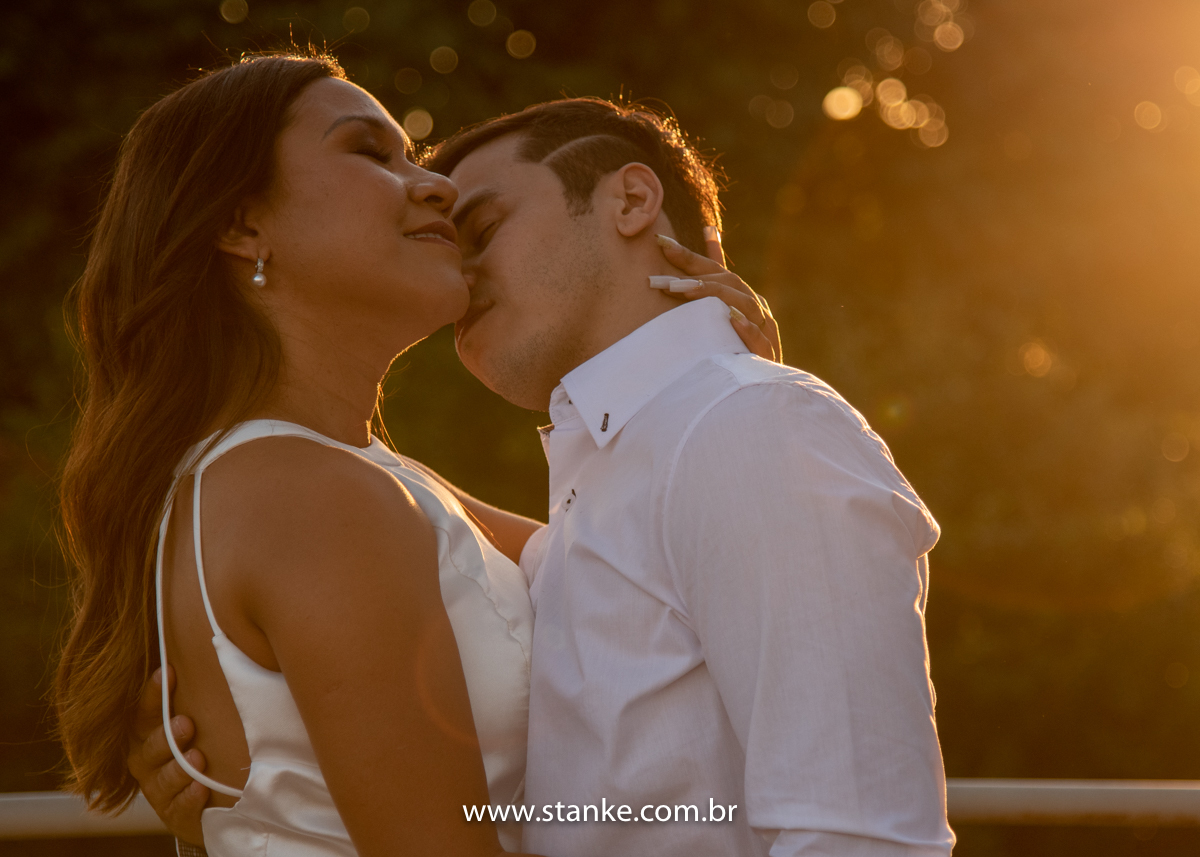 Ensaio pós casamento de Giseli e Aurélio, Aurélio dando um cheiro no pescoço da e raios do por do sol ao fundo. Fotos feitas no Memorial Ferroviário, em Campo Grande-MS, por Pedro Stanke.