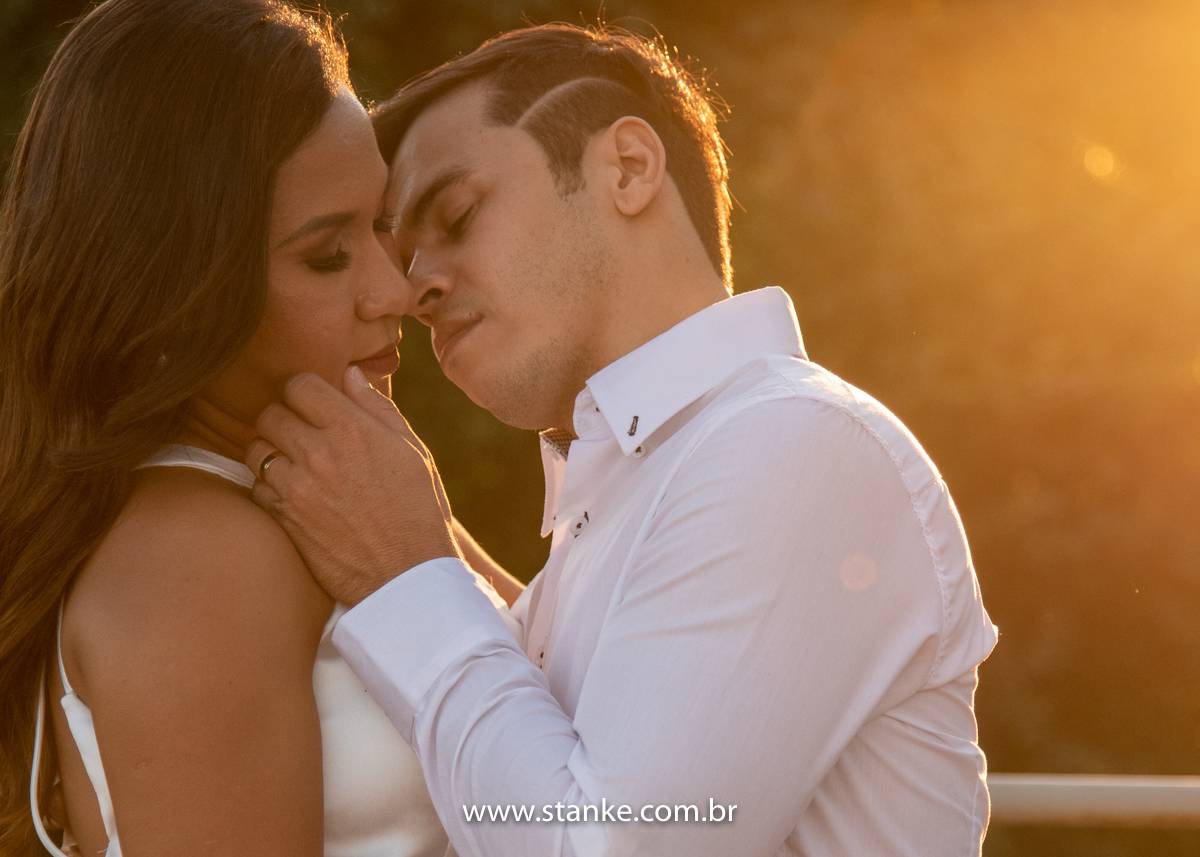 Ensaio pós casamento de Giseli e Aurélio, Aurélio fazendo carinho no rosto da Giseli e raios do por do sol ao fundo. Fotos feitas no Memorial Ferroviário, em Campo Grande-MS, por Pedro Stanke.