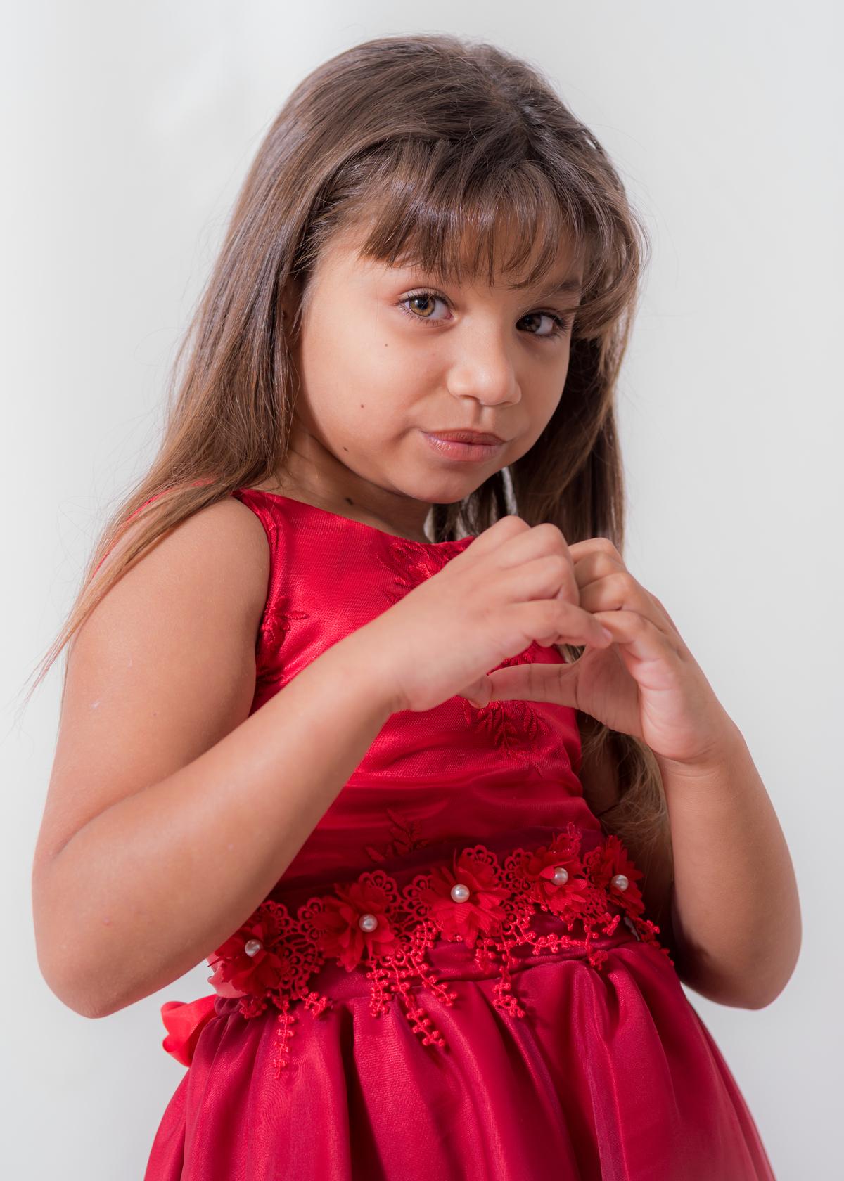 Ensaio em estúdio da Júlia 09 anos,  Com um olhar cativante olhando para câmera e fazendo um coração com as mãos. Fotos feitas em Campo Grande-MS, pelo fotógrafo Pedro Stanke.