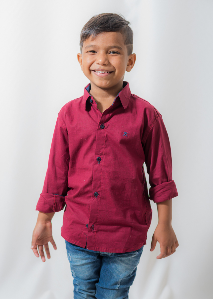 Ensaio Artur, de 07 anos, com a sua camisa vermelha e calça Jens manchada. De frente com os braços meio abertos  e olhando para câmera com sorriso gostoso. Fotos feitas em Campo Grande-MS, pelo fotógrafo Pedro Stanke.