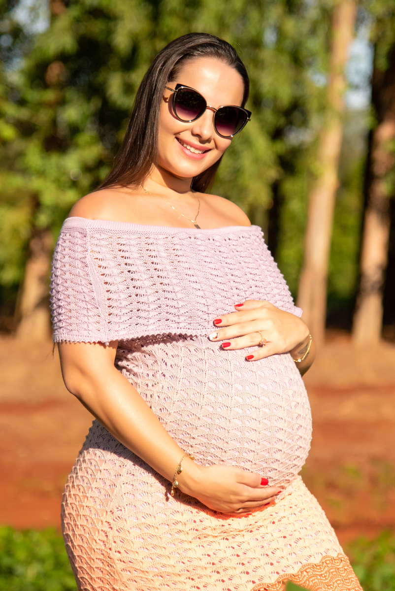 Ensaio gestante, Gestante com as mãos na barriga e olhando para o fotógrafo, e no fundo eucaliptos. Fotos feitas em Campo Grande-MS, por Pedro Stanke, fotógrafo de família e fotógrafo de gestantes.