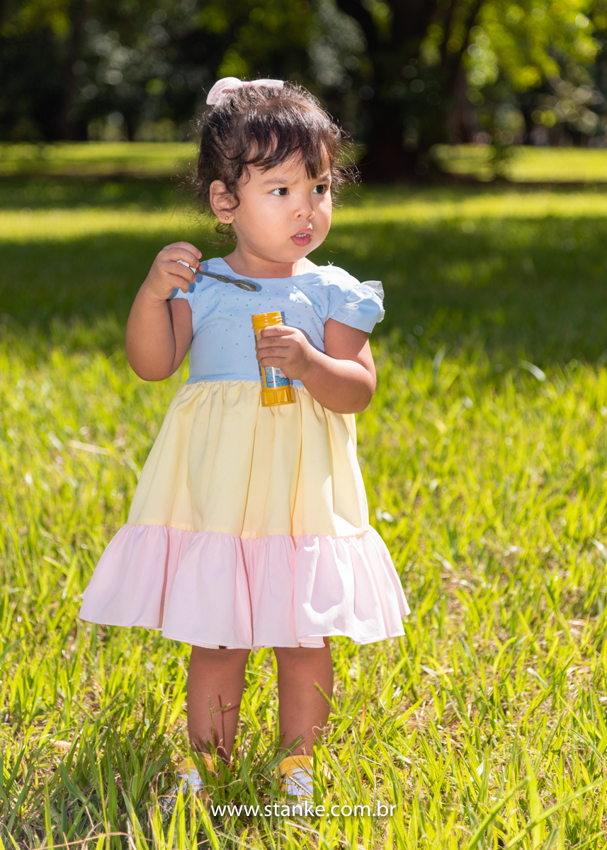 Ensaio infantil da Clara com 2 anos, Aniversariante, com seu vestido colorido,  fazendo bolhinhas de sabão. Fotos feitas no Bosque da Paz, pelo fotógrafo Pedro Stanke. 