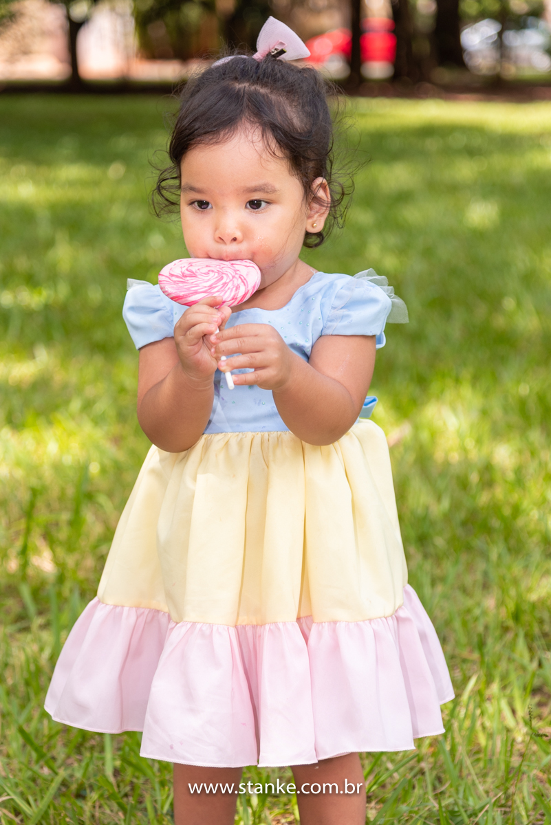 Ensaio infantil da Clara com 2 anos, Aniversariante, com seu vestido colorido,  e saboreando o seu enorme pirulito em espiral e colorido. Fotos feitas no Bosque da Paz, pelo fotógrafo Pedro Stanke. 