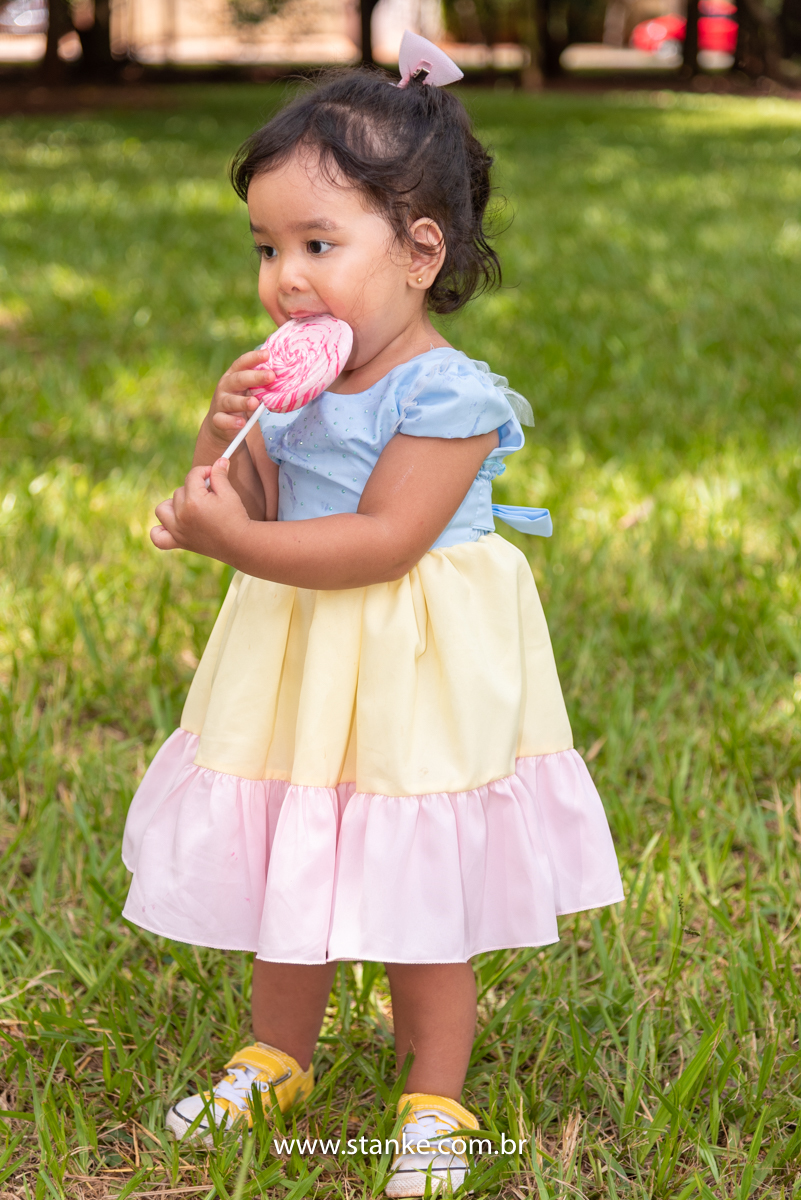 Ensaio infantil da Clara com 2 anos, Aniversariante, com seu vestido colorido e tênis amarelo, tudo combinando. E saboreando o seu  pirulito, com as mãos melecadas. Fotos feitas no Bosque da Paz, pelo fotógrafo Pedro Stanke. 
