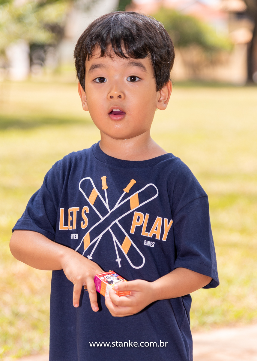 Ensaio infantil do Davi com 4 anos, Aniversariante, olhando para câmera enquanto segura a caixinha de estralinhos. Fotos feitas no Bosque da Paz, pelo fotógrafo Pedro Stanke. 