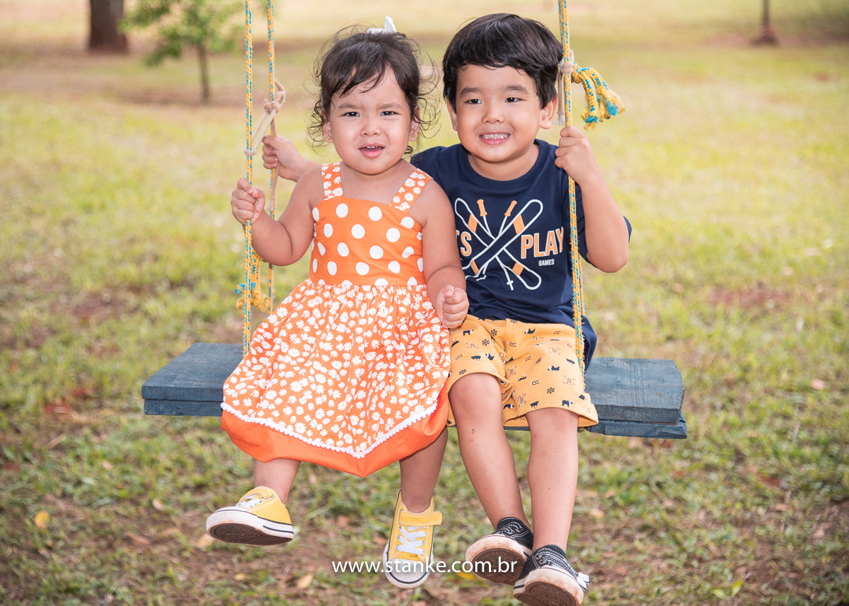 Ensaio infantil do Davi com 4 anos, Aniversariante com a sua irmã, ambos sentados no balanço e olhando para câmera. Fotos feitas no Bosque da Paz, pelo fotógrafo Pedro Stanke. 