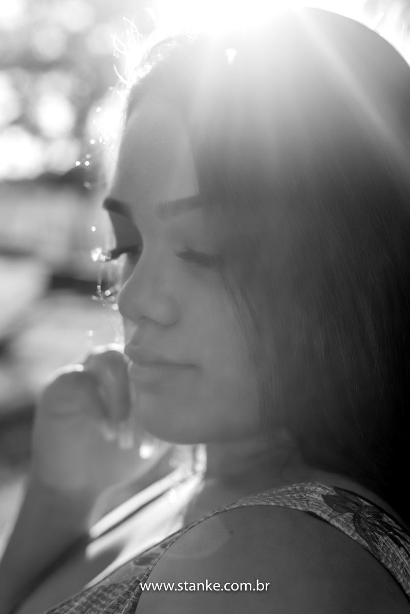 Ensaio 15 anos externo, um close bem fechado em preto e branco, da aniversariante com olhar abaixado e de lado, e com uma das mãos no rosto. Fotos realizadas Estância Mariana perto Campo Grande-MS. Fotógrafo Pedro Stanke.