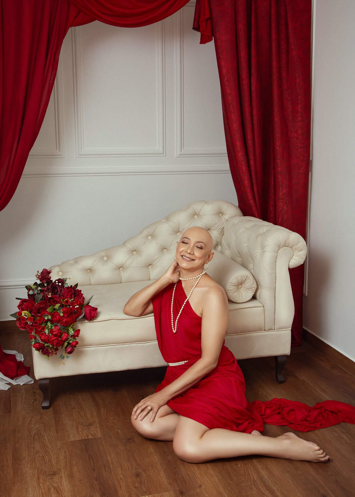 mulher sorrindo com colar de pérolas escorada no recamier