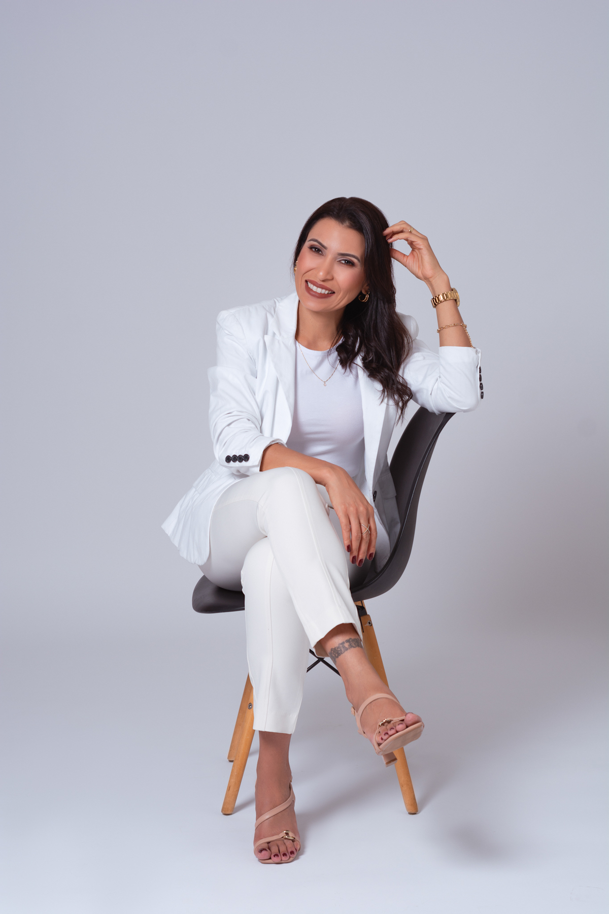 Sentada com a mão na cabeça e com sorriso simpático no rosto