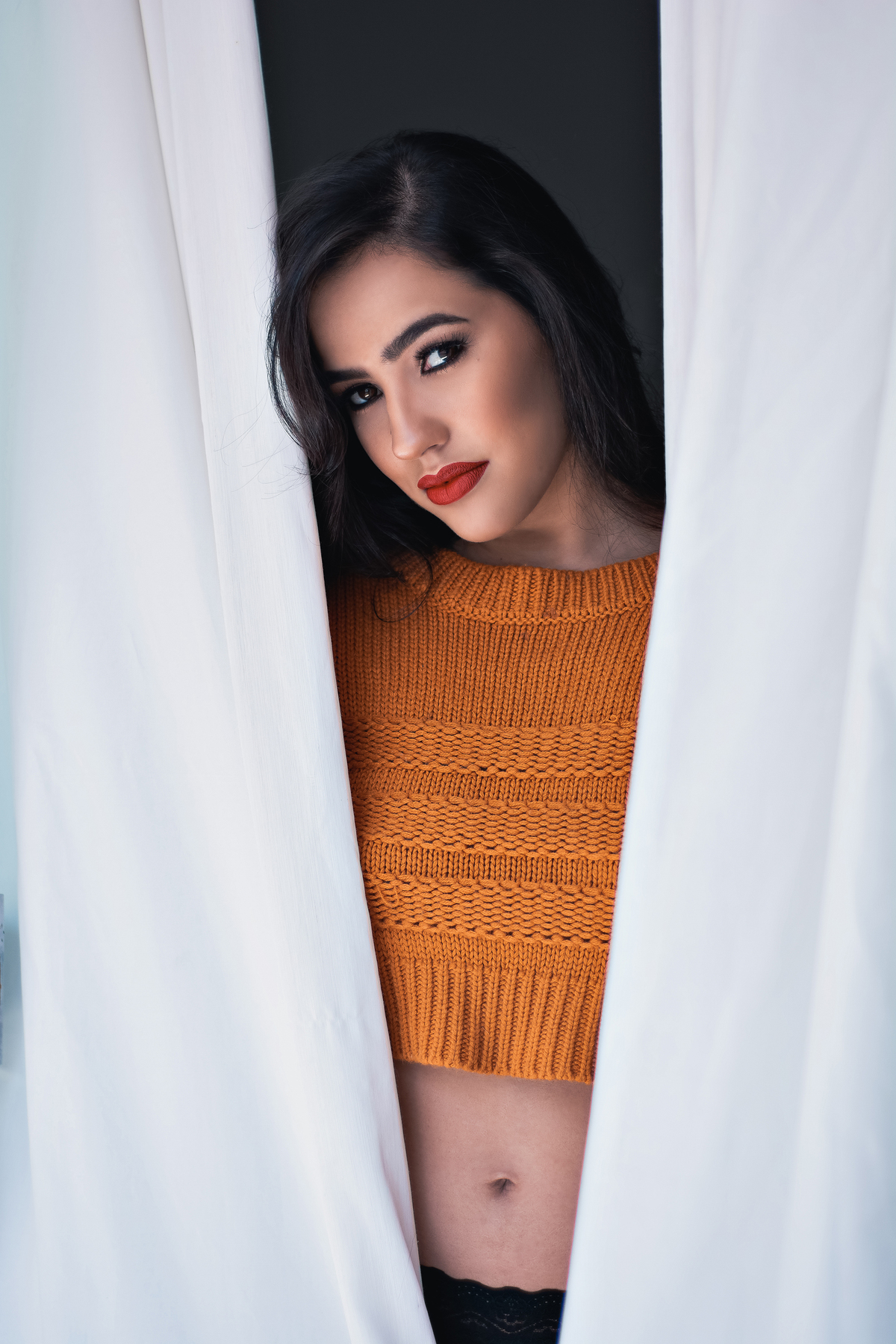 abraçando a cortina com olhar marcante
